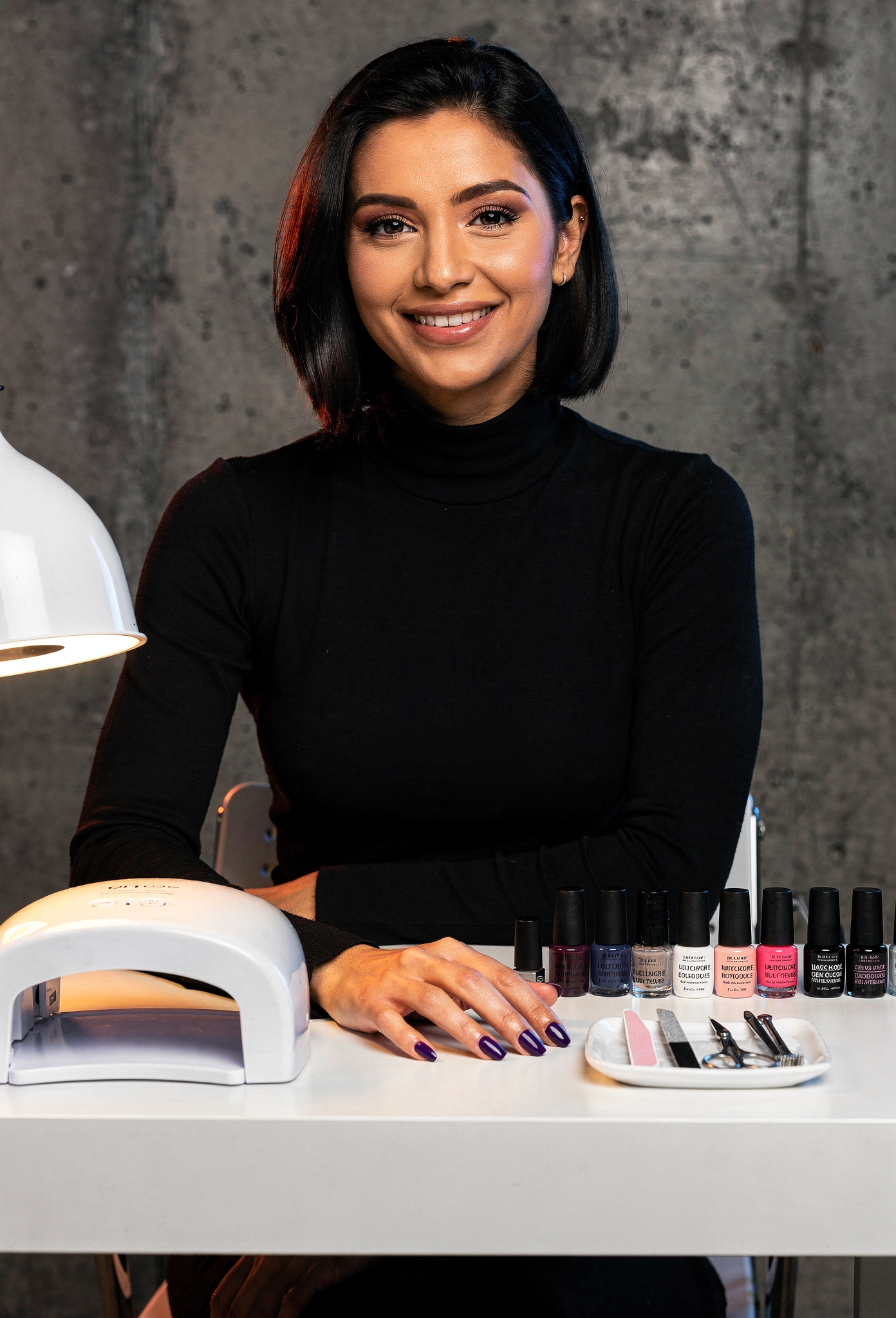 Siyah boğazlı kazaklı kıdemli nail artist styling istasyonunda oturuyor periwinkle tırnaklarla