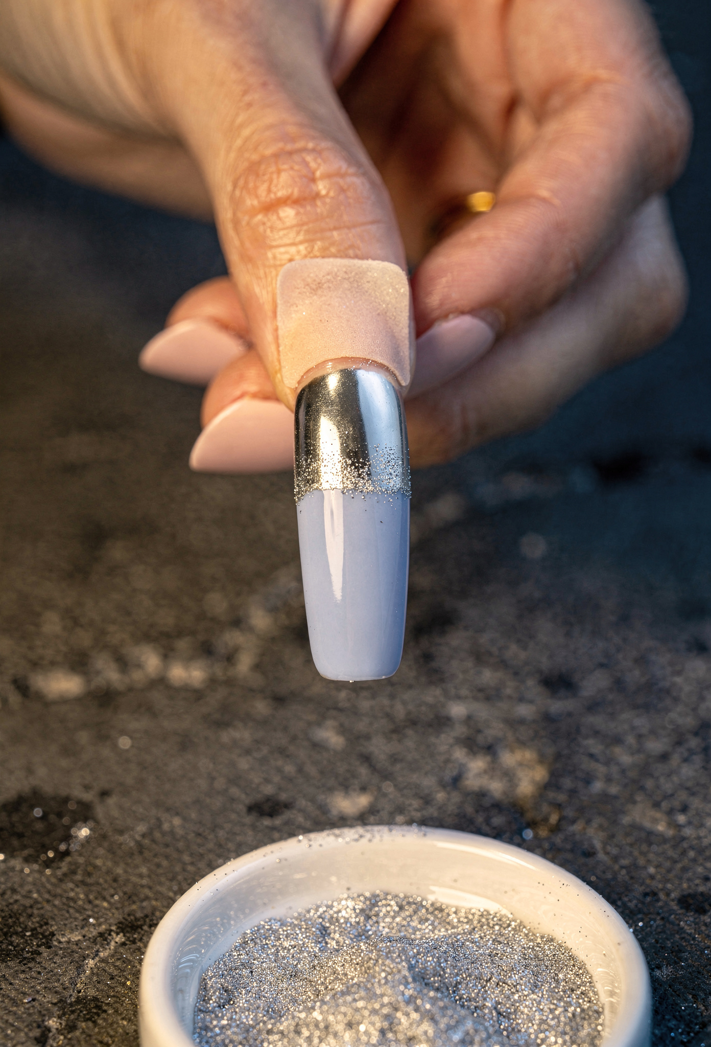 Nail artist krom tozu uygularken yakın çekim periwinkle jel üzerine ayna efekti